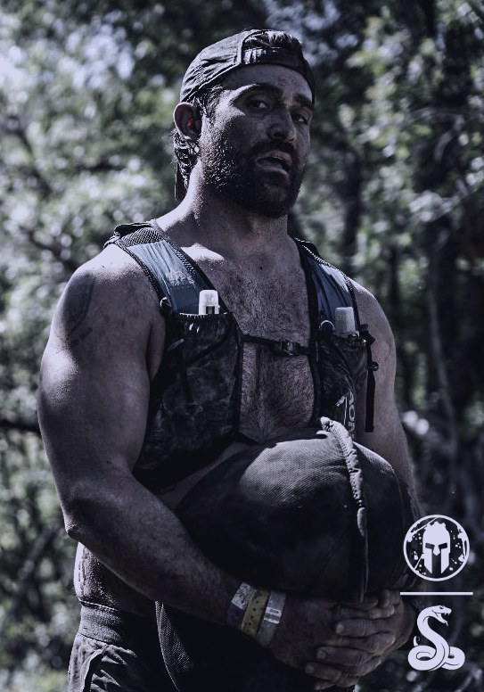RK carrying a sandbag, covered in mud, during a Spartan race.