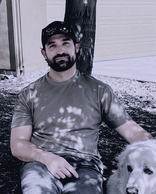 RK, seated outdoors with his dog.